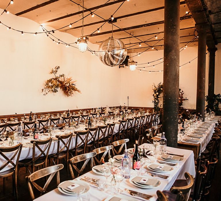 Reception decor with floral installations and festoon lighting at Clapton Country Club wedding