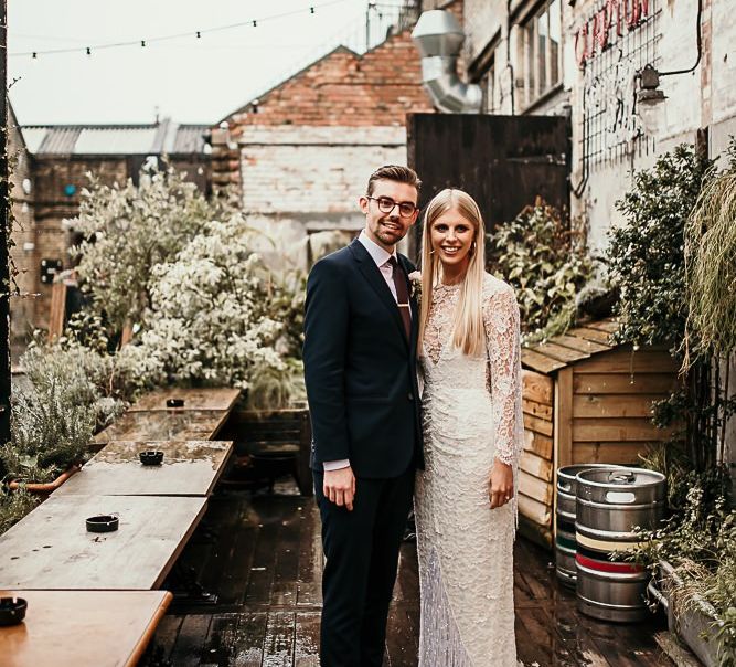 Bride and groom embrace at city celebration with botanical styling and foliage decor in East London