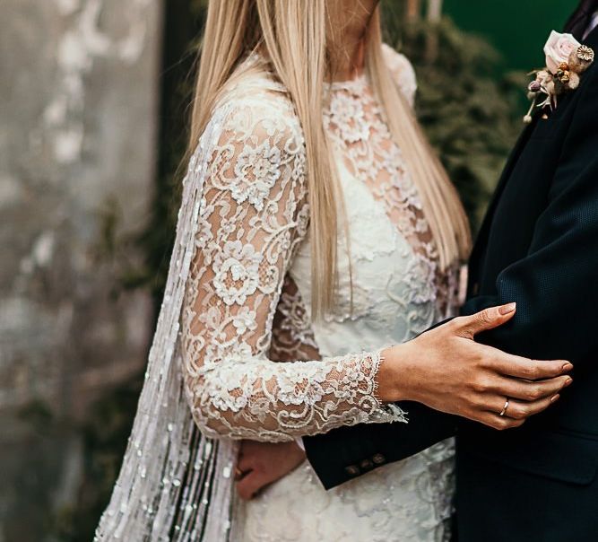 Bride and groom embrace at city celebration with botanical styling wearing a lace boho style dress