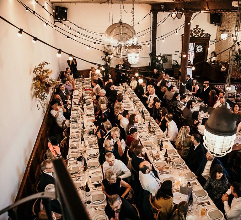 Reception decor with foliage details and festoon lighting for contemporary celebration