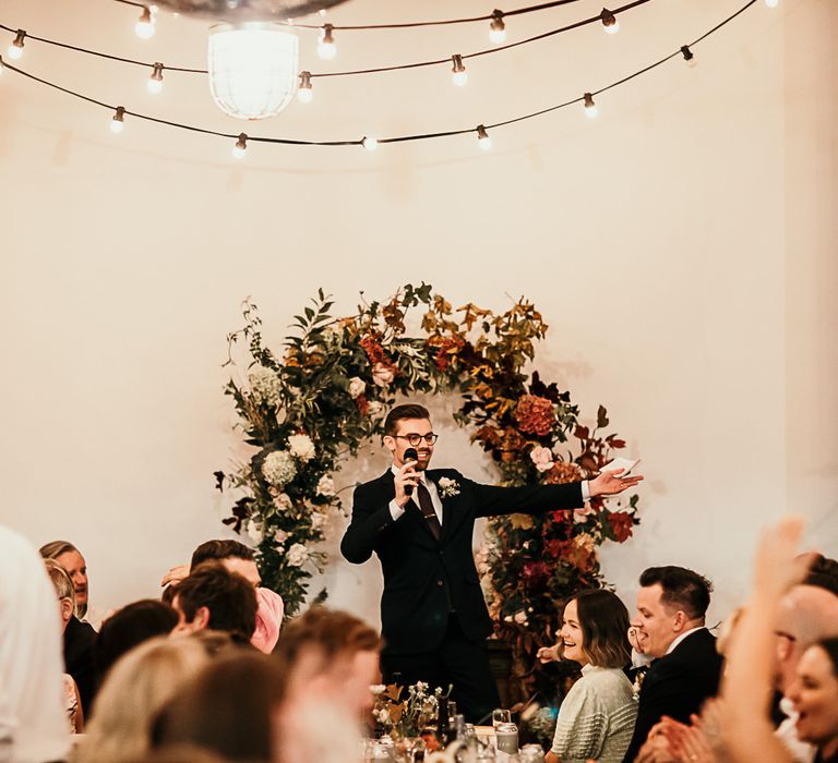 Reception decor with foliage details and festoon lighting at Clapton Country Club wedding