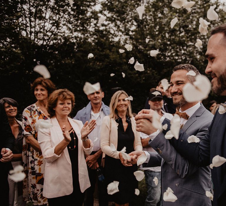 Confetti moment for grooms bow ties and wedding suits