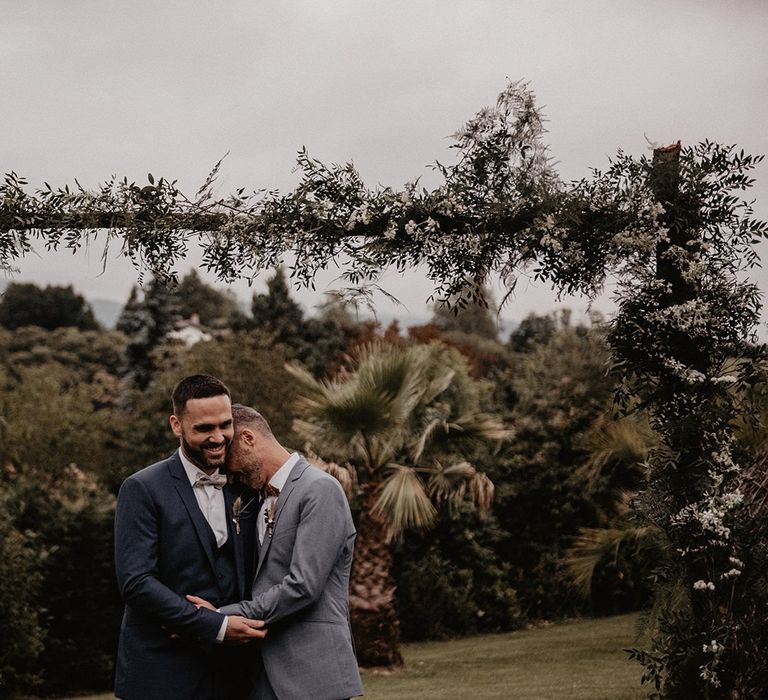 Grooms bow ties and wedding suits under wooden arch