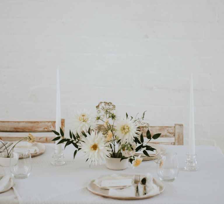 Minimalism table decor with white candles and flower centrepiece