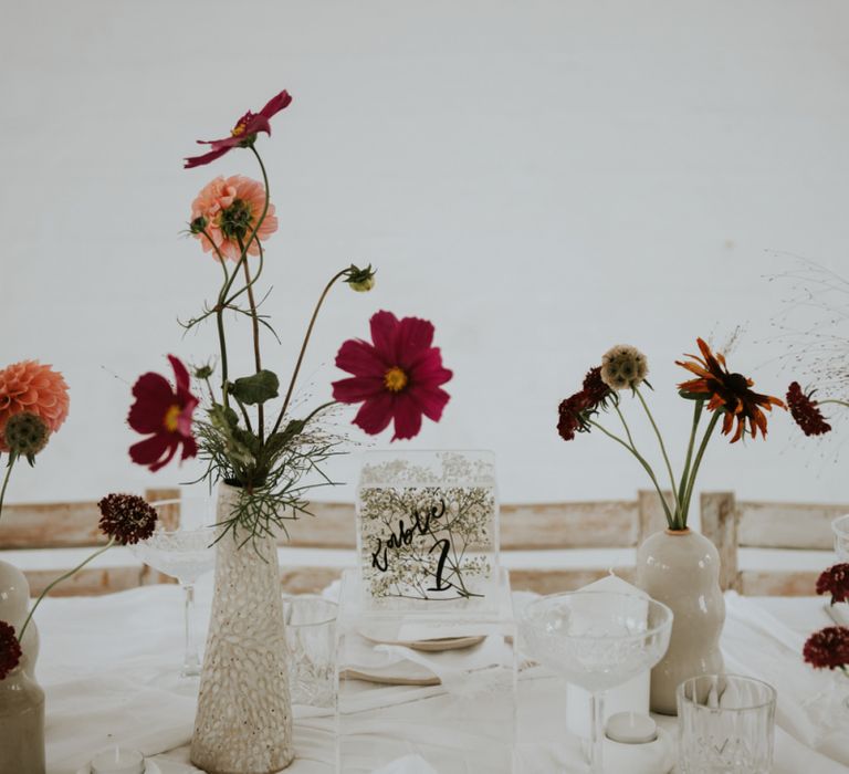 Vases and ink well centrepieces filled with flower stems for minimalist wedding