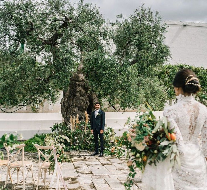 Groom in Navy Suit Waiting for His Bride at the Altar with Floral Arrangements