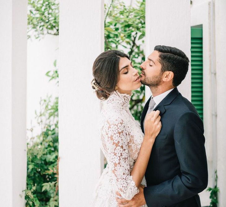 Bride in Lace Wedding Dress and Groom in Navy Suit Embracing