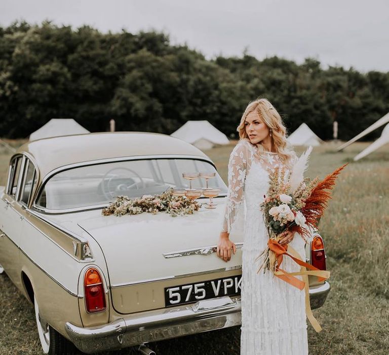 Boho Bride in Lace Wedding Dress Standing Next to a Vintage Wedding Car