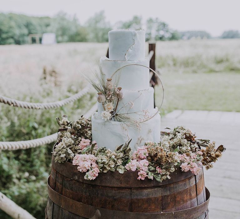 White Wedding Cake with Flower Skirt on a Wooden Barrel