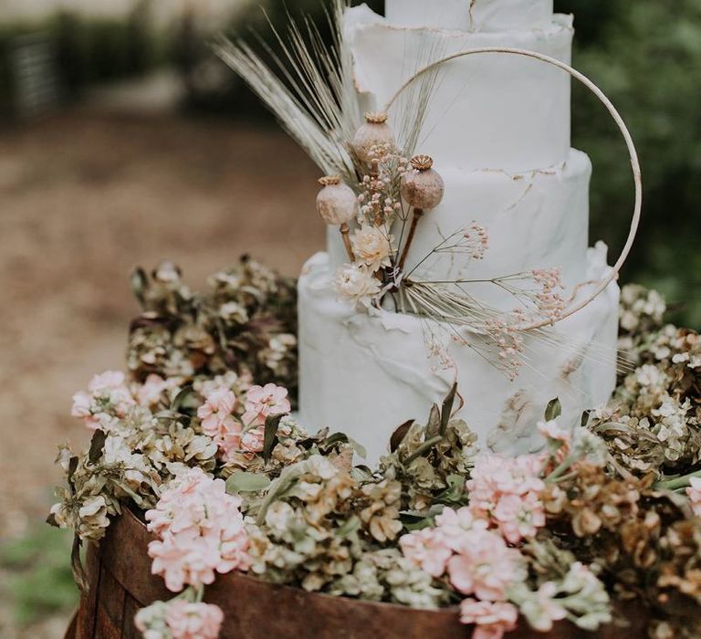 White Wedding Cake with Dried Flower and Hoop Decor on a Wooden Barrel