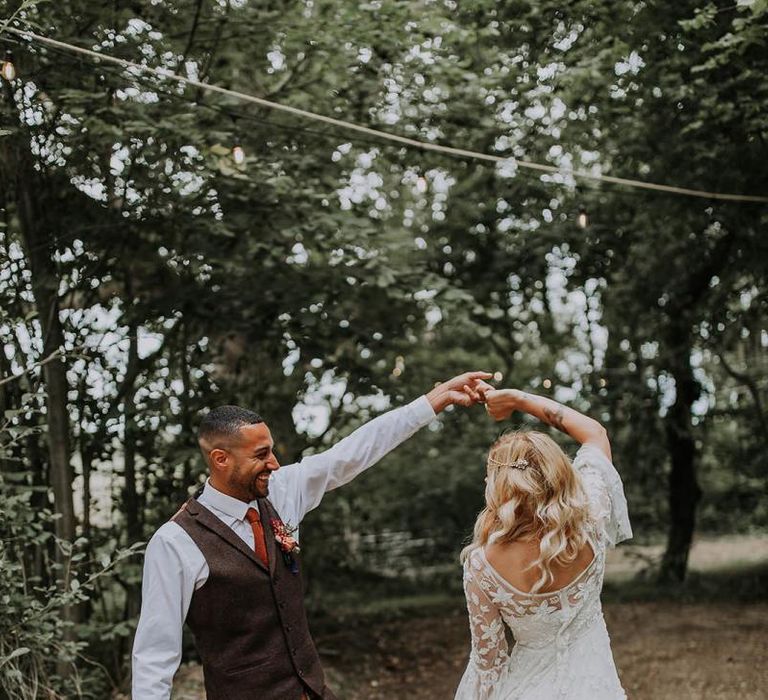 Groom in Wool Waistcoat  Twirling His Bride in a Lace Wedding Dress in the Woods