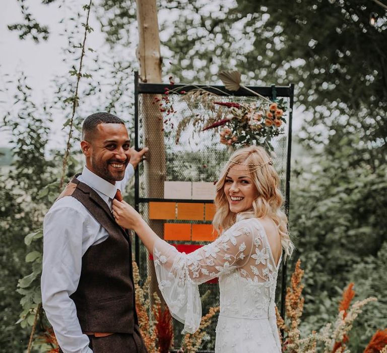 Boho Bride and Groom Standing Next to Their Extravagant Table Plan