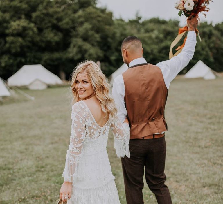 Boho Bride and Groom Walking Through the Fields Towards Their Bell Tent