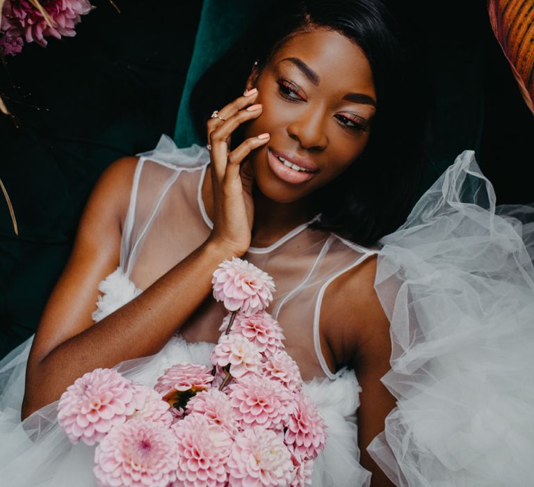 Bride with illusion neckline wedding dress holding a pompom bouquet