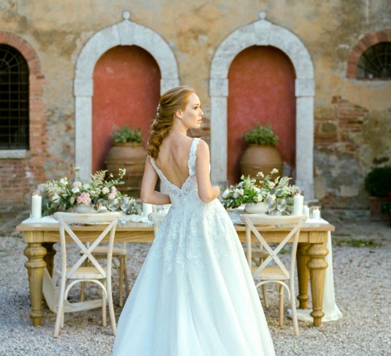 Bride in Lace Sorrisi di Gioia Wedding Dress Standing in Front of a Rustic Tablescape