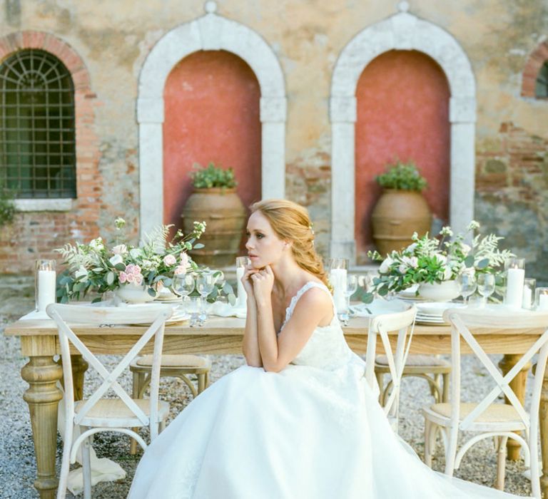 Bride in Lace Sorrisi di Gioia Wedding Dress Sitting at Rustic Tablescape