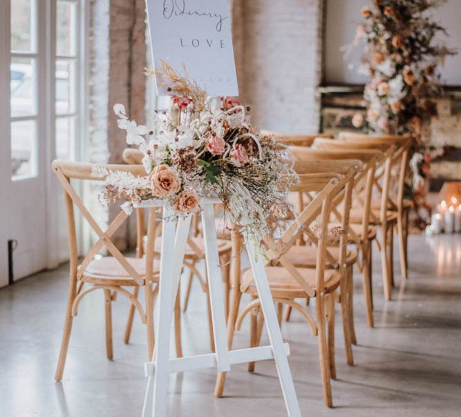 Wedding ceremony sign on white easel with orange flowers