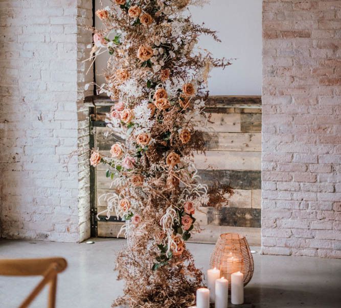 Vertical wedding flower arrangement with orange flowers and foliage