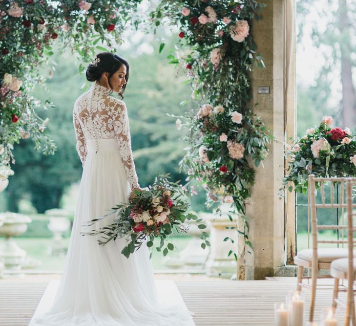 Bride at the Floral Arch Altar in Lace Bodice Suzanne Neville Wedding Dress | Blush &amp; Burgundy Floral Fairytale Wedding Inspiration at Grittleton House Planned &amp; Styled by Jennifer Louise Weddings | Katherine Yiannaki Photography