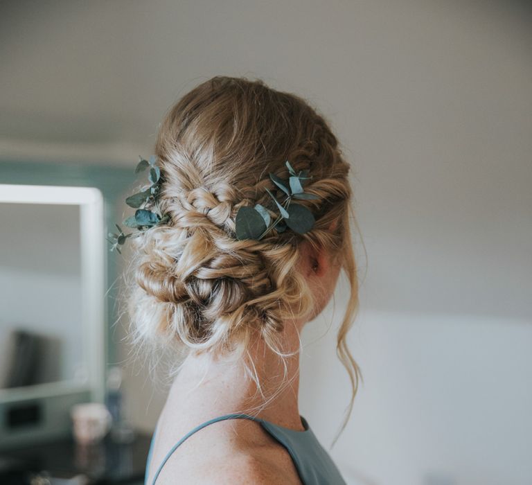 Bridesmaid with eucalyptus in braided, pinned wedding updo