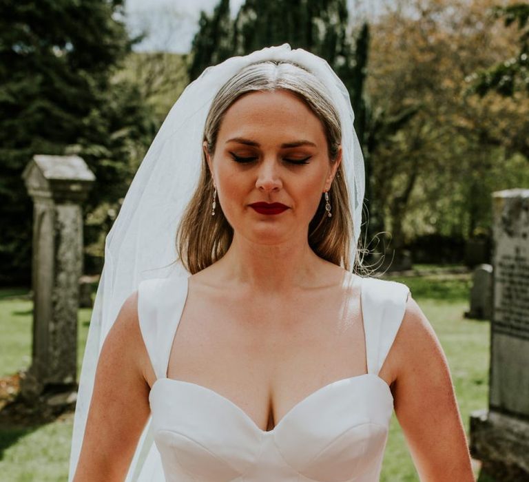 Bride takes a moment in fitted wedding dress before church ceremony