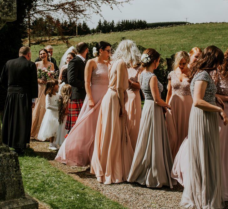 Bridesmaid in mismatched dresses make their way to the ceremony