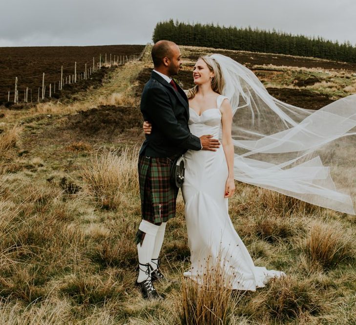 Brides veil blows in the wind for Scottish wedding with hanging flowers