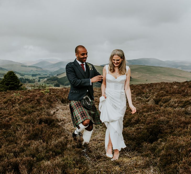 Bride and groom stroll through fields at Scottish wedding