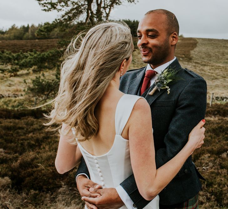 Bride and groom steal a moment during wedding with hanging flowers