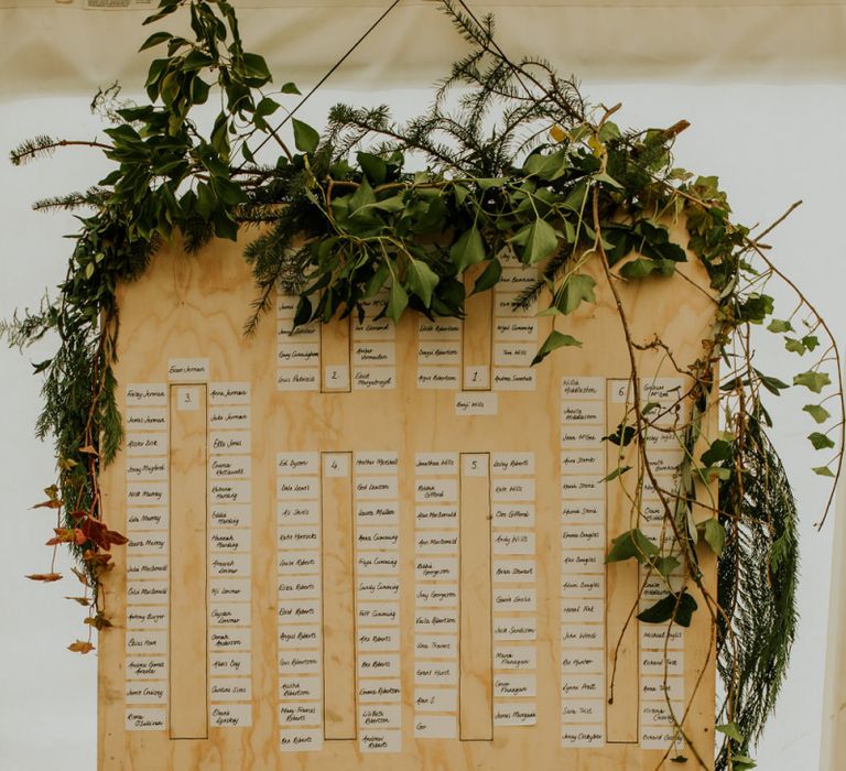 Wooden wedding table plan with foliage decor