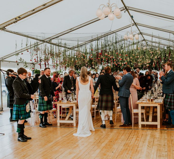 Bride and groom mingle with guests underneath hanging flowers