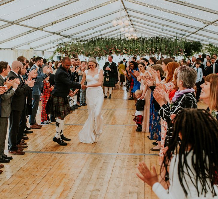 Scottish ceilidh underneath hanging flowers at marquee wedding