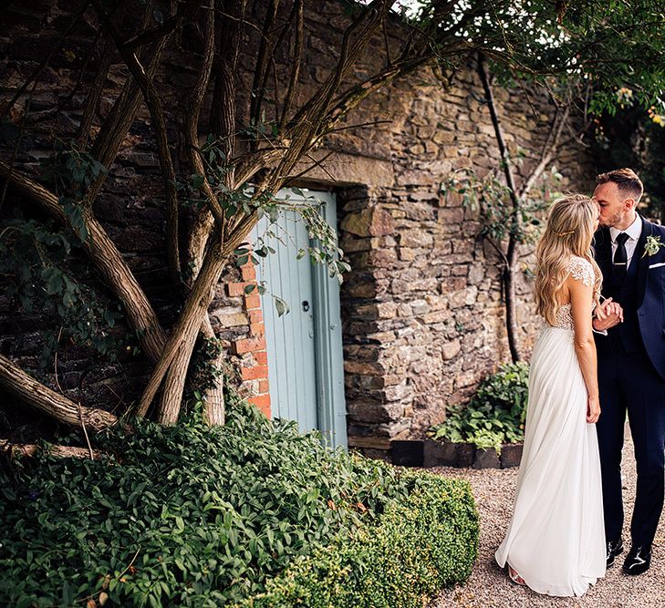 Bride and groom kissing in the gardens at Kingston Estate in Devon