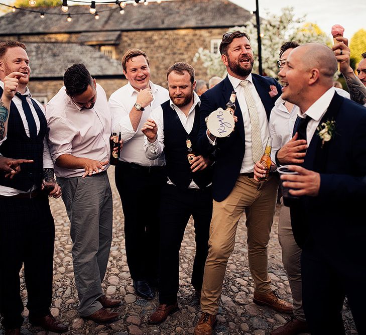 Groomsmen gathered in the courtyard with tambourines and beers