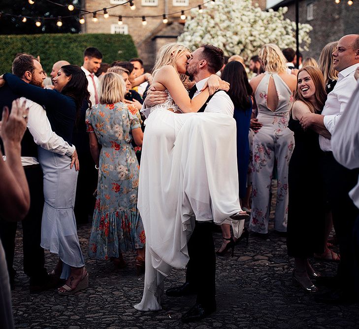 Groom picking up his bride during outdoor wedding first dance