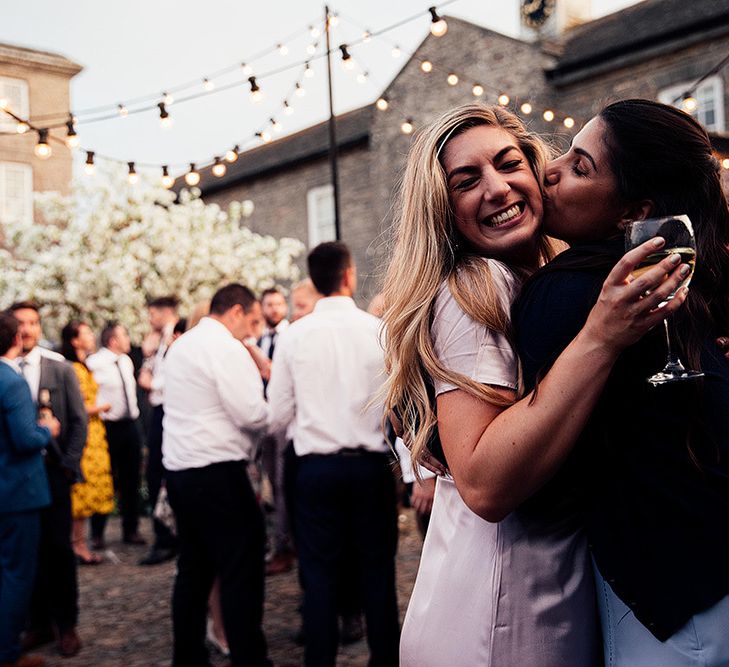 Wedding guests hugging at outdoor evening reception