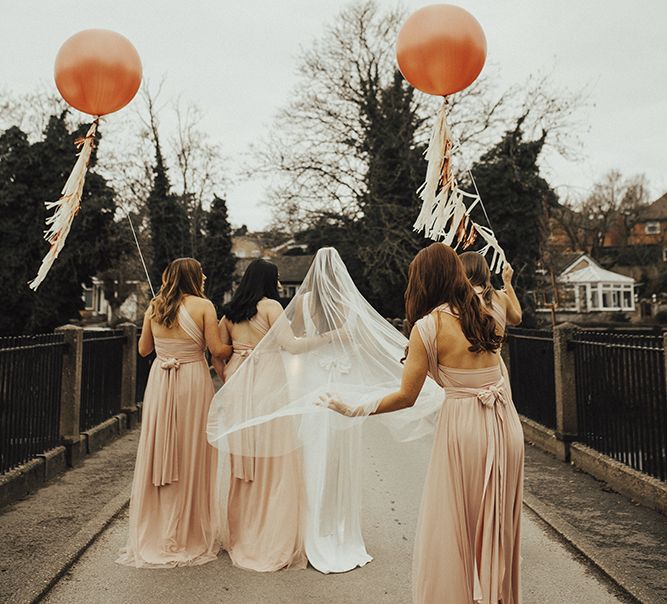 Bridal Party Portrait with Bridesmaids in Pink Victoria Lou Bridal Multiway Dresses with Tulle Holding Giant Balloons with Tassels