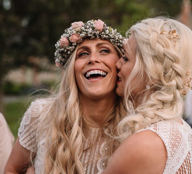 Bride wearing braided undo and other bride in flower crown