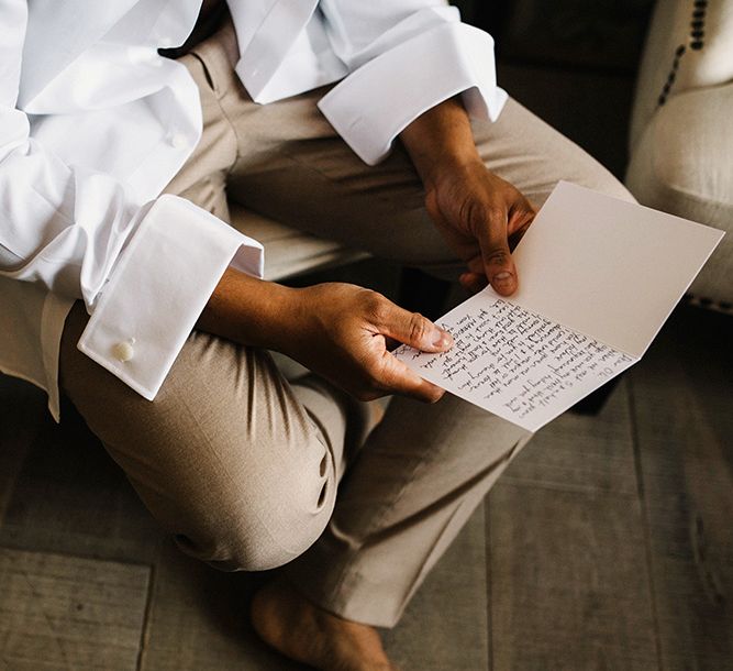 Groom in Beige Moss Bros. Suit Reading a Wedding Card