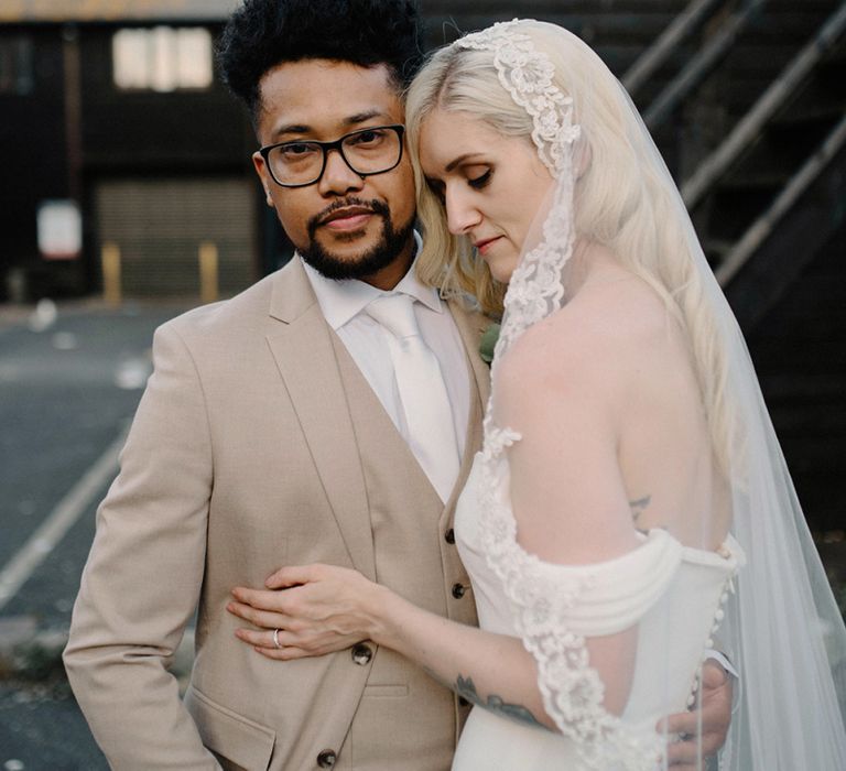 Bride in Pronovias Wedding Dress Embracing her Groom in a Beige Moss Bros. Suit