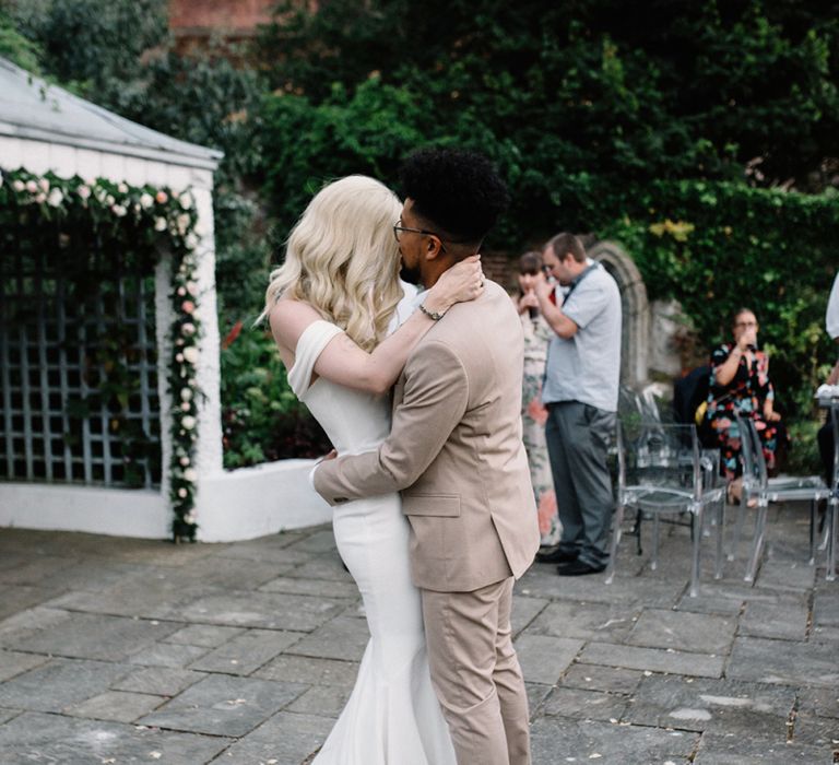 Bride in Pronovias Wedding Dress and Groom in a Beige Moss Bros. Suit Having Their First Dance Together