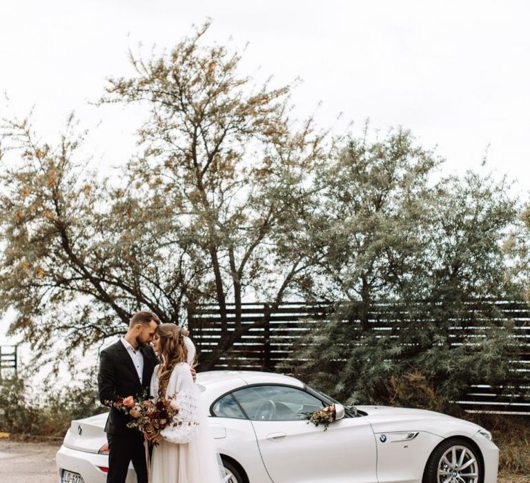 Bride and Groom Standing Next to Their BMW Z3 Convertible White Wedding Car