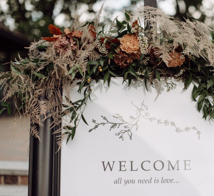 Wedding Welcome Sign Decorated with Muted Wedding Flowers and Dried Foliage