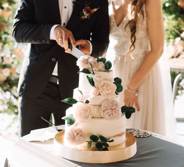 Bride and Groom Cutting the Semi Naked Wedding Cake Decorated with Fresh Flowers