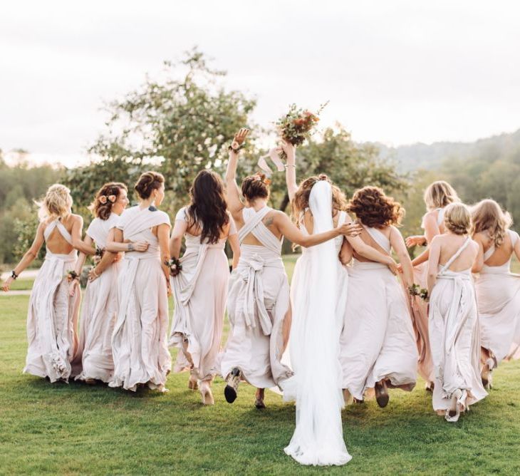 Bridal Party Portrait with Bridesmaids in Oyster Multiway Dresses and Bride in Fay Katya Katya Wedding Dress Skipping Through The Fields