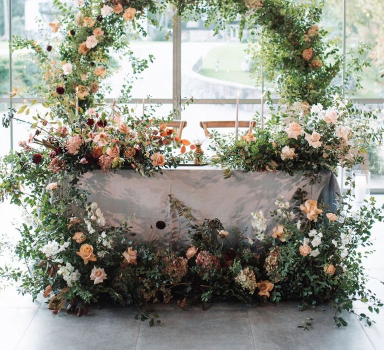 Sweetheart Table with Moon Gate Backdrop and Floral Arrangements in Front of The Table