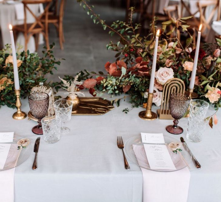 Sweetheart Table Place Settings with Gold Candlesticks, Glass Charger Plates and muted Flower Arrangements