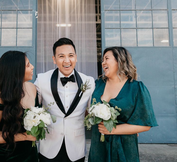 Groom in white dinner jacket with two of his bridesmaids