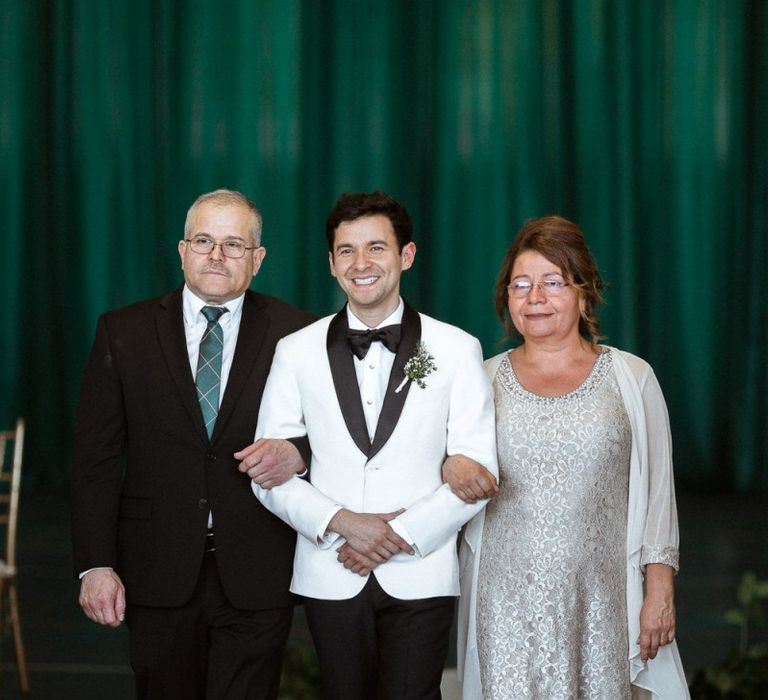 Groom walking down the aisle with his parents