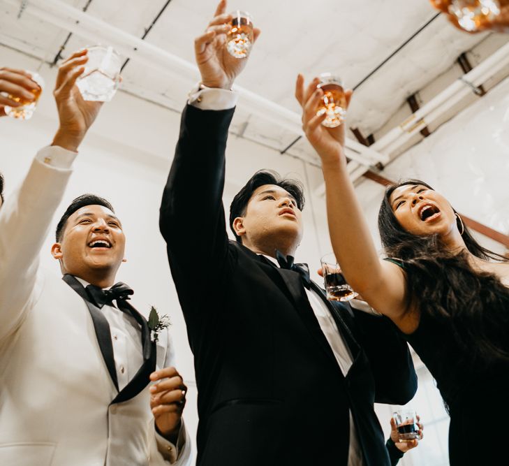 Grooms raising their glass at industrial wedding